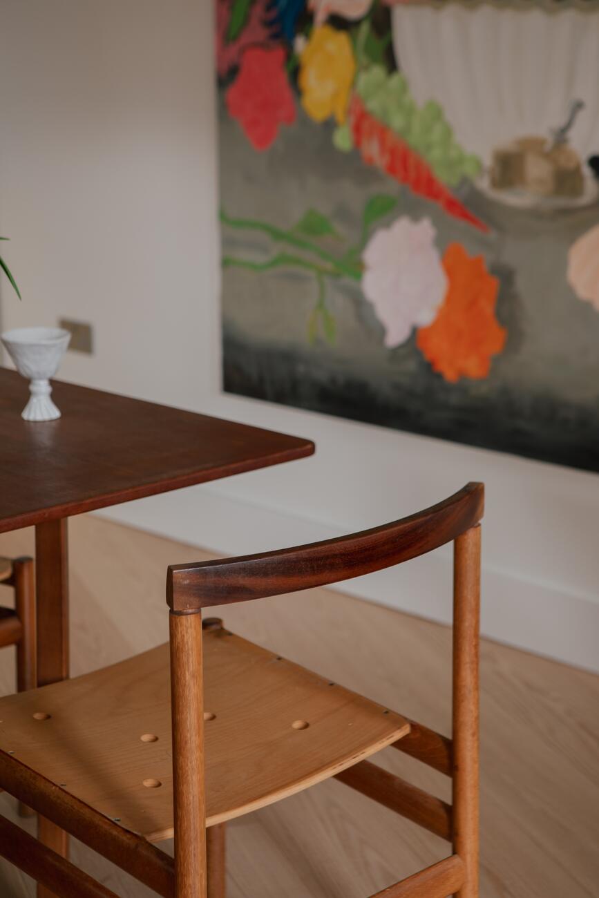 Timber dining chair and table beneath a large painting