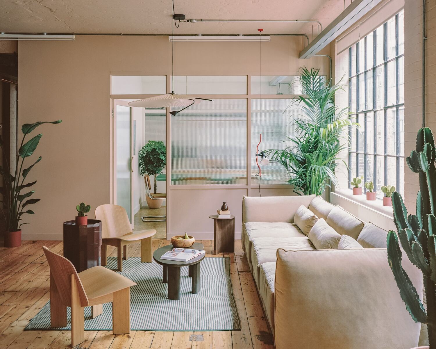 A FolkTale Projects interior: warehouse room with pink walls, reeded glass partition, cream sofa and plants